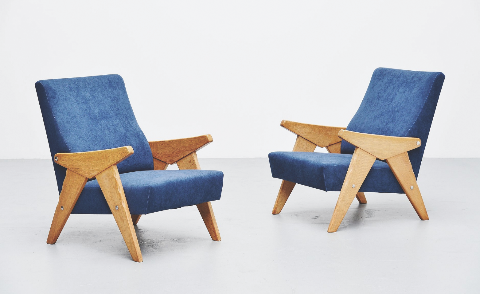 A pair of 1960s lounge chairs with a solid oak frame upholstered in blue velvet www.massmoderndesign.com