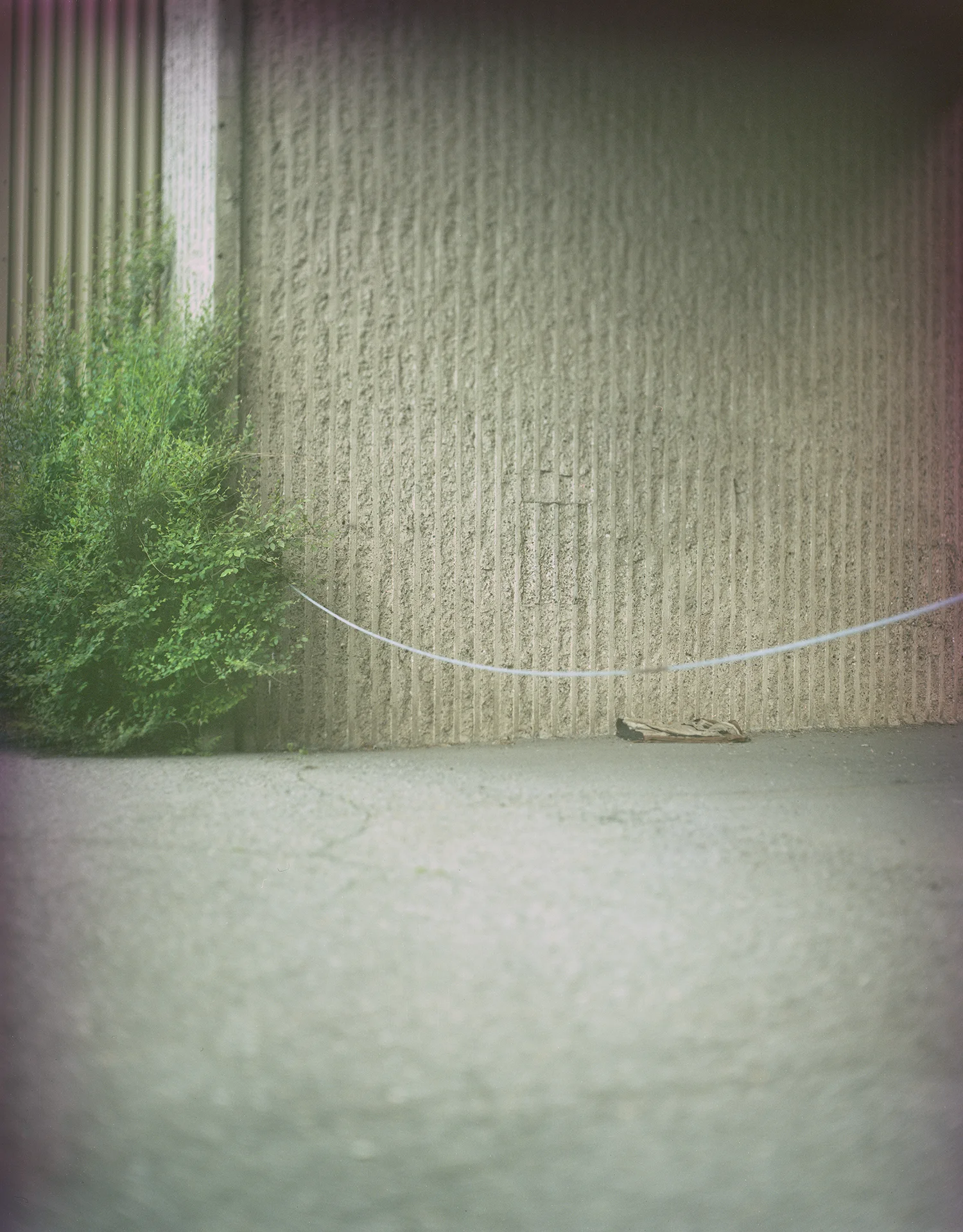 Expired 0003: Parking Lot under the Montreal Train Station (Source: Machinski, 2018). An abandoned mat perhaps used for sleeping. The area around this parking lot is worn and weathered with weeds growing out of small cracks in the concrete. 
