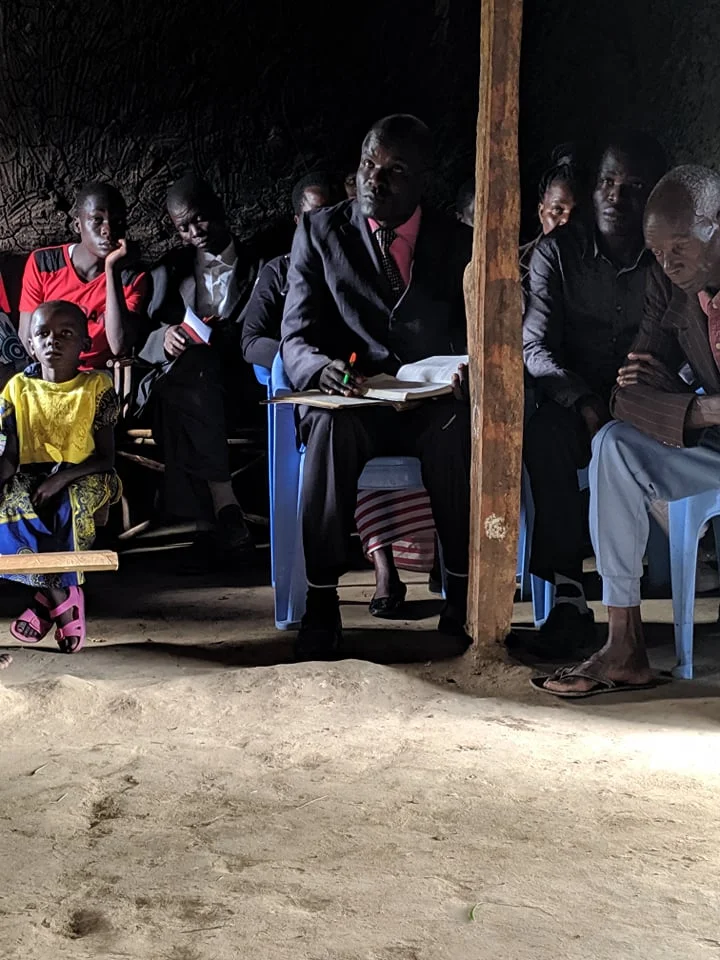 Wearing the tie and pink shirt is Patrick, a visitor to the church. He pastors a church in another village.