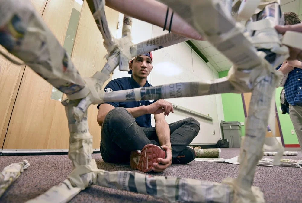 Design team instructor Cody Nelson watches the progress of his team's newspaper tower at the Science Museum of Minnesota in St. Paul on a recent Saturday. Nelson, who served time in prison for manslaughter, turned to prevention programs to steer himself away from gangs and violence. Richard Marshall for MPR News