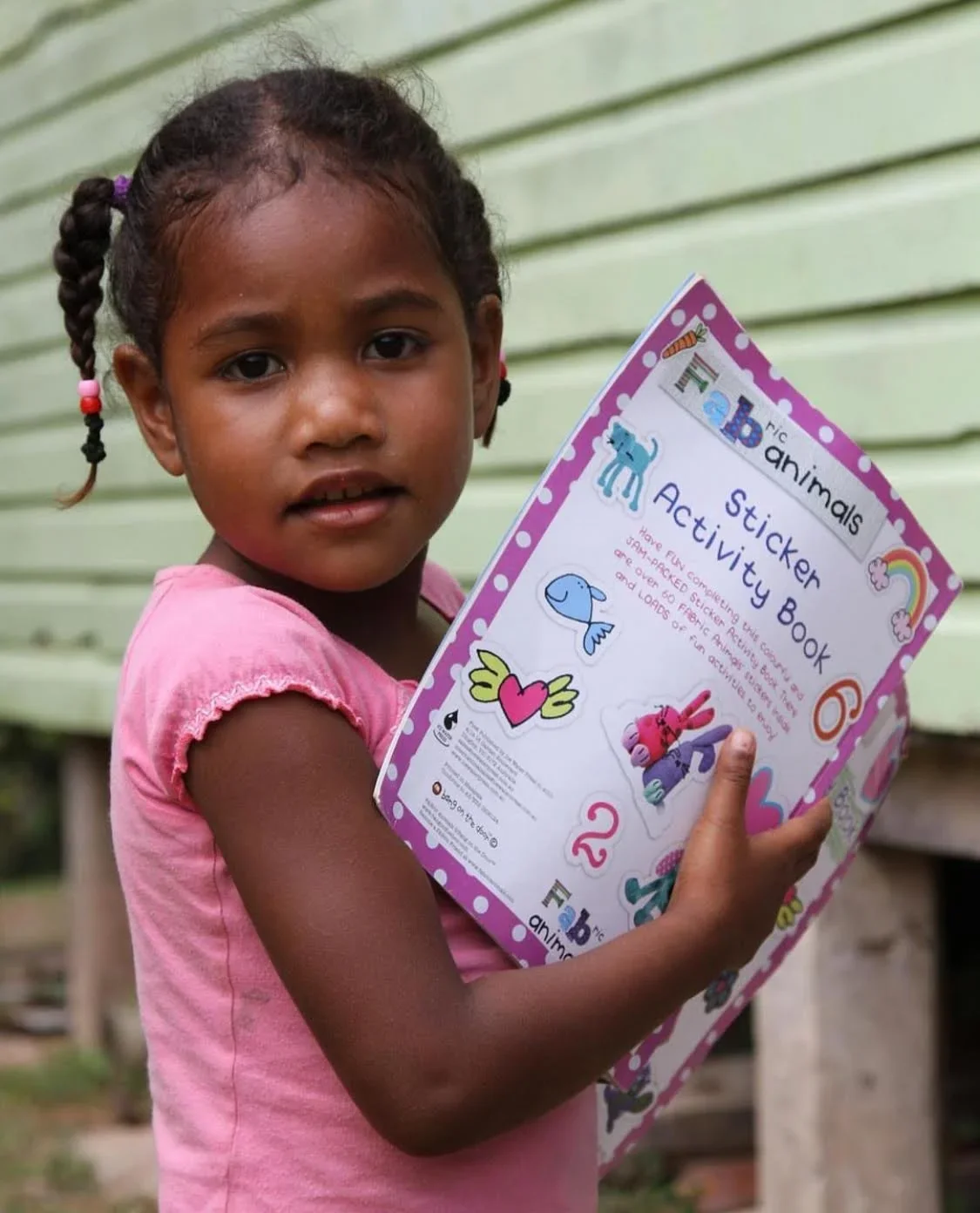 A young Fijian girl holding a book.