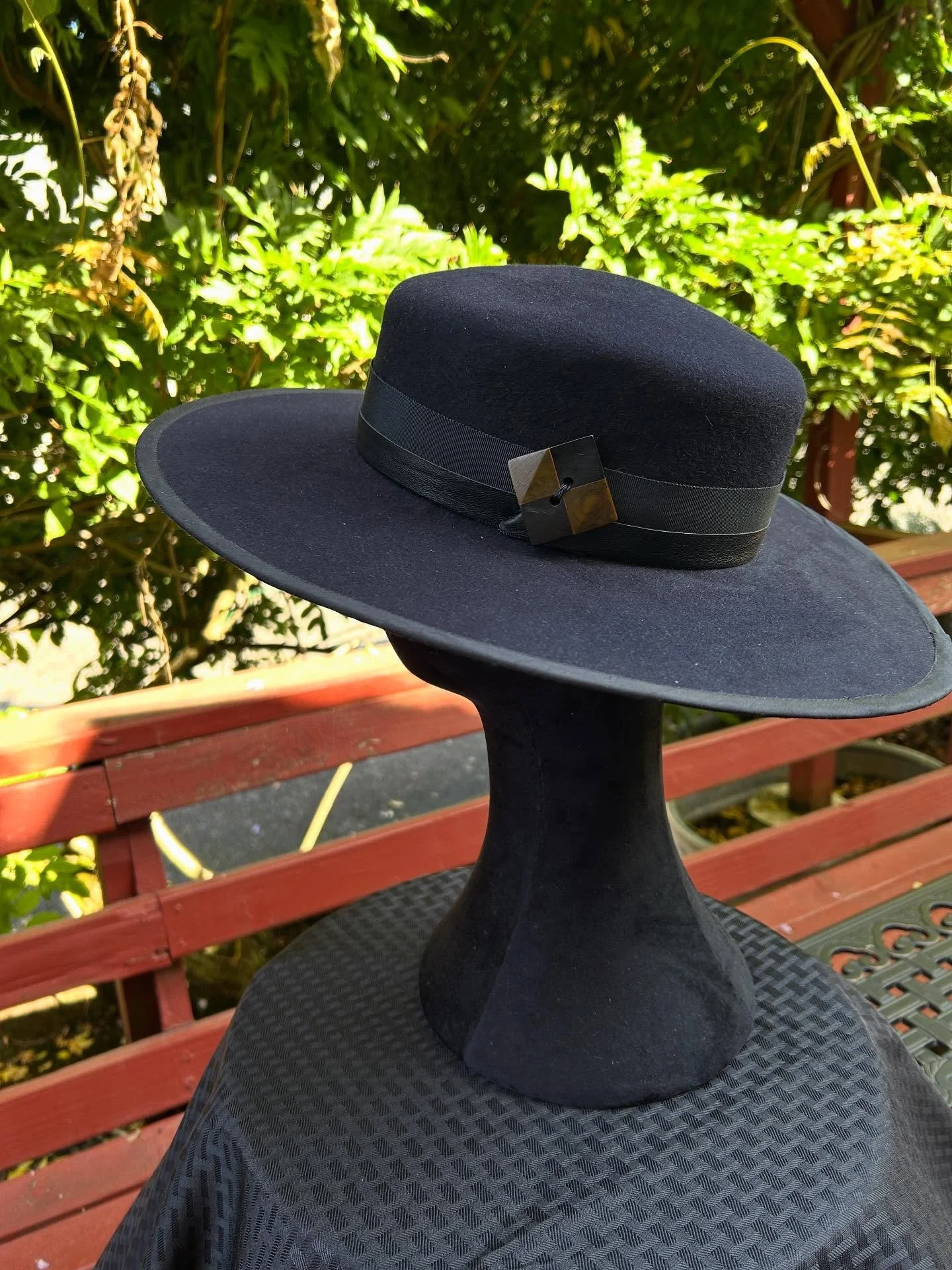 Hand blocked, black fur felt with flat brim and straight sided crown put out for sale this morning. Black petersham edging and a double band around the crown, one a wide petersham and the other leather, finished off with a great over sized two toned 
