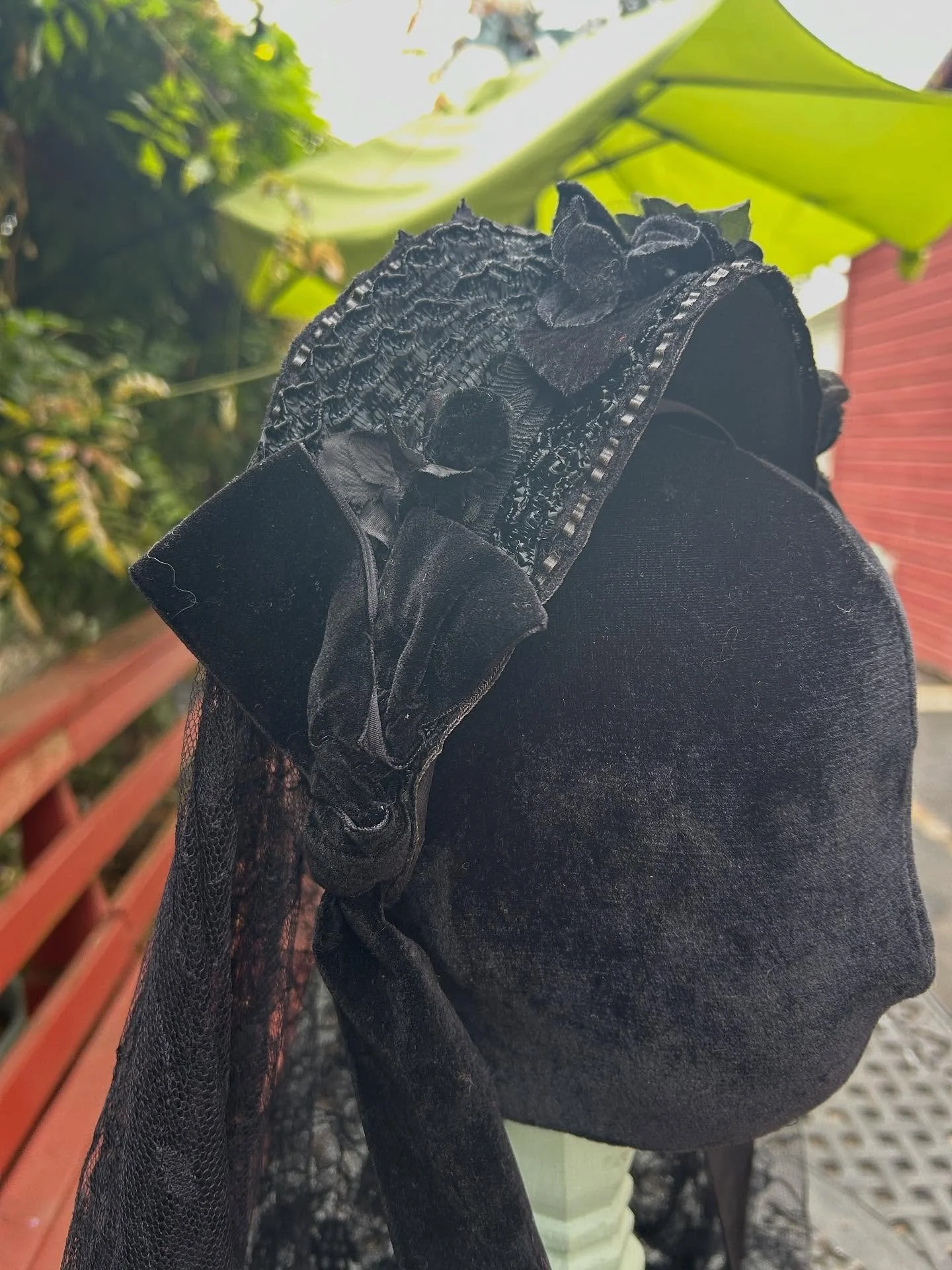 Wire frame covered in ice wool followed by black silk then hand-sewn black straw over the silk and decorated with handmade silk flowers are just the start of this bustle era headpiece. Black velvet ties  and loops along  with a Chantilly lace veil wi