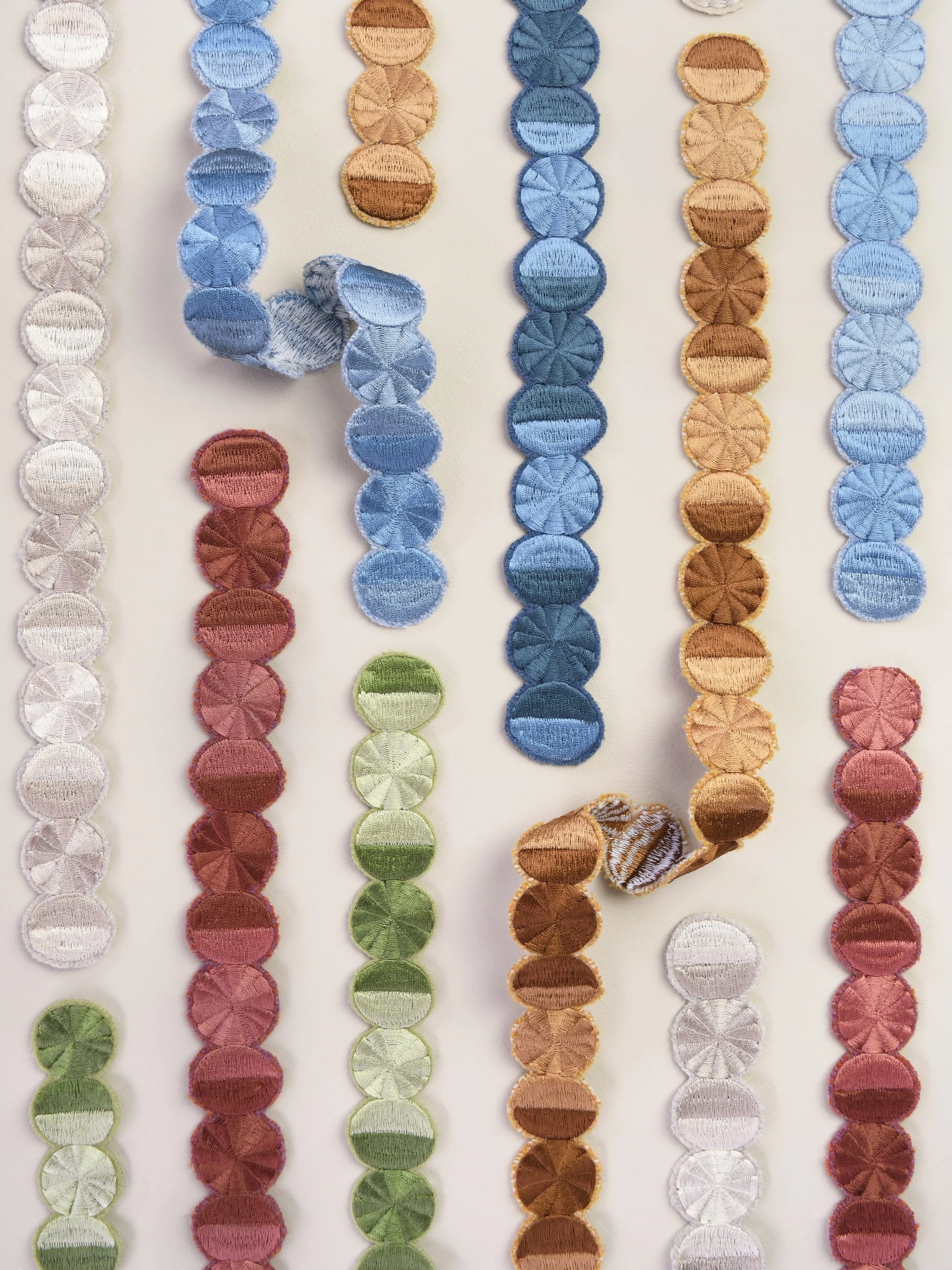 Embroidered circles in multi-colour threads by Imogen Heath — a detail of decorative passementerie stitched on a white background.