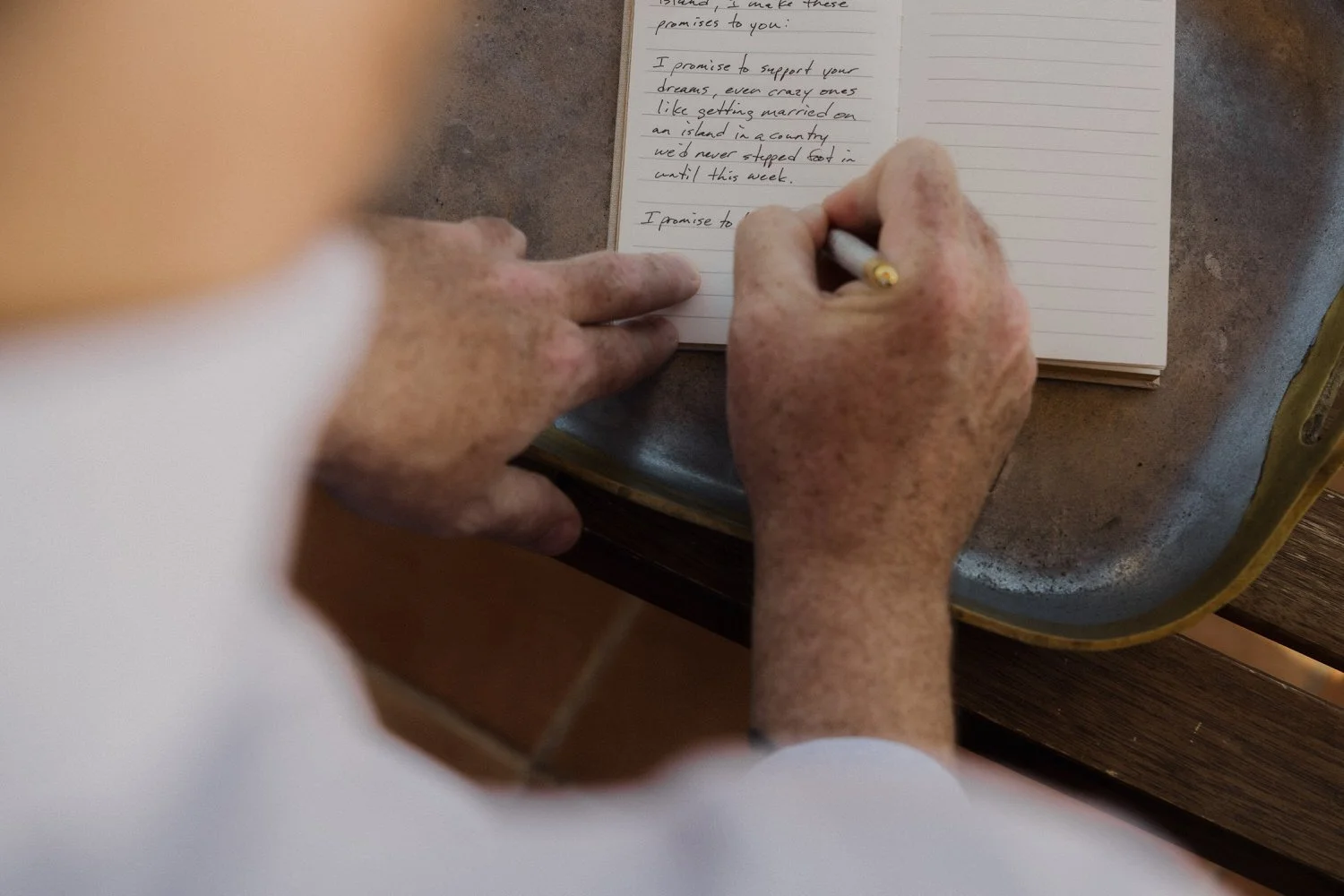 Close-up of the groom writing his vows by hand in a notebook, capturing a raw and emotional pre-wedding moment during an intimate elopement in Mallorca. A quiet promise on paper before the ceremony begins.