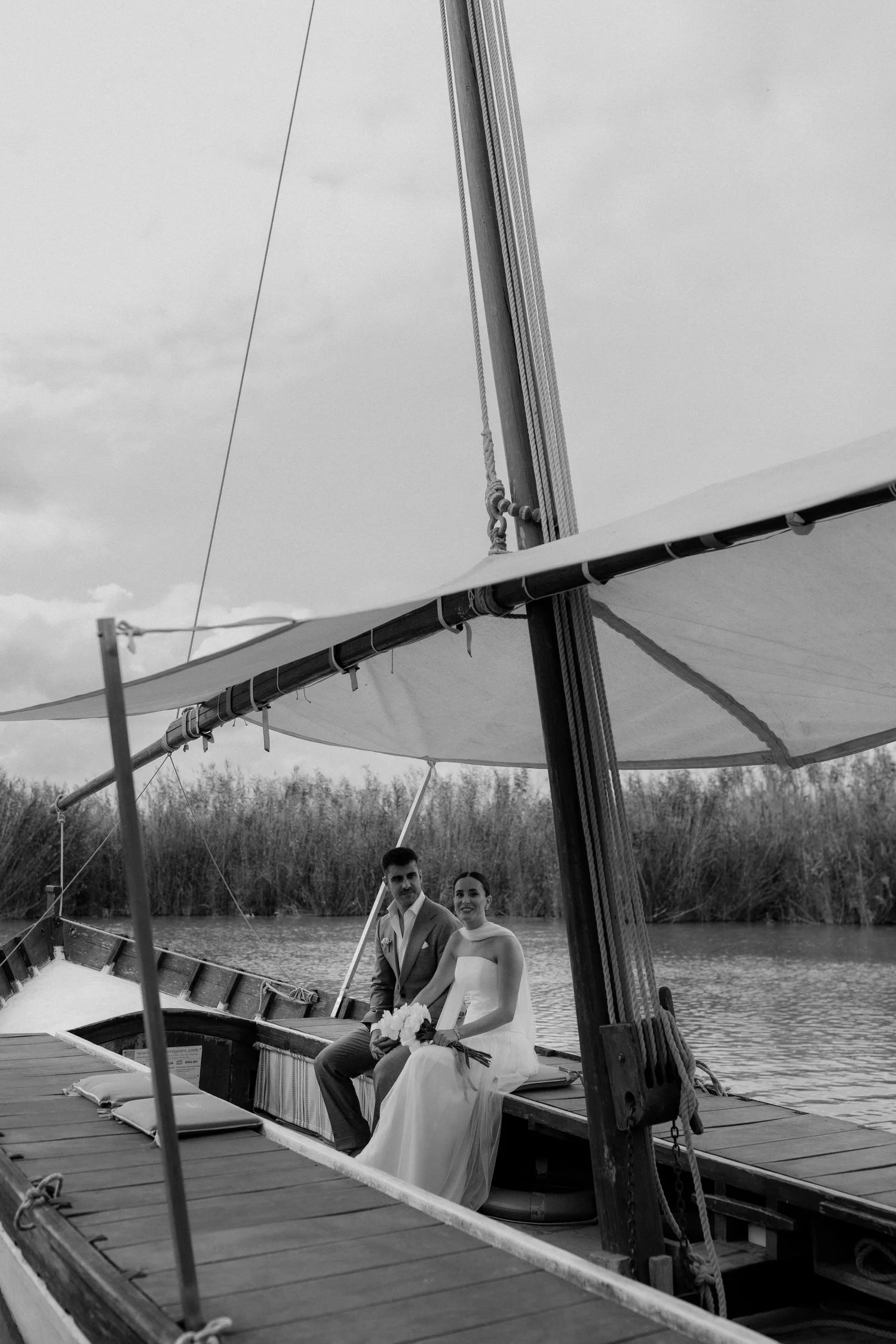 Bride arriving by traditional boat with her brother across the Albufera before the ceremony at La Barraca del Palmar