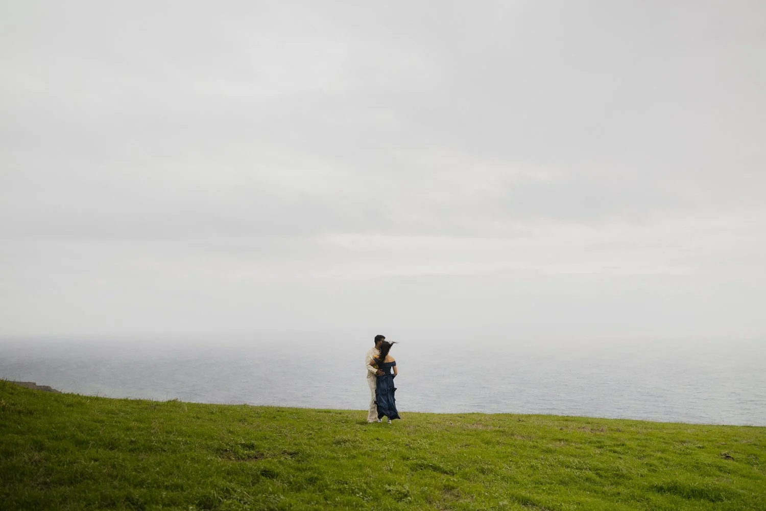 Couple embracing on a remote cliff overlooking the Atlantic Ocean in São Miguel Azores