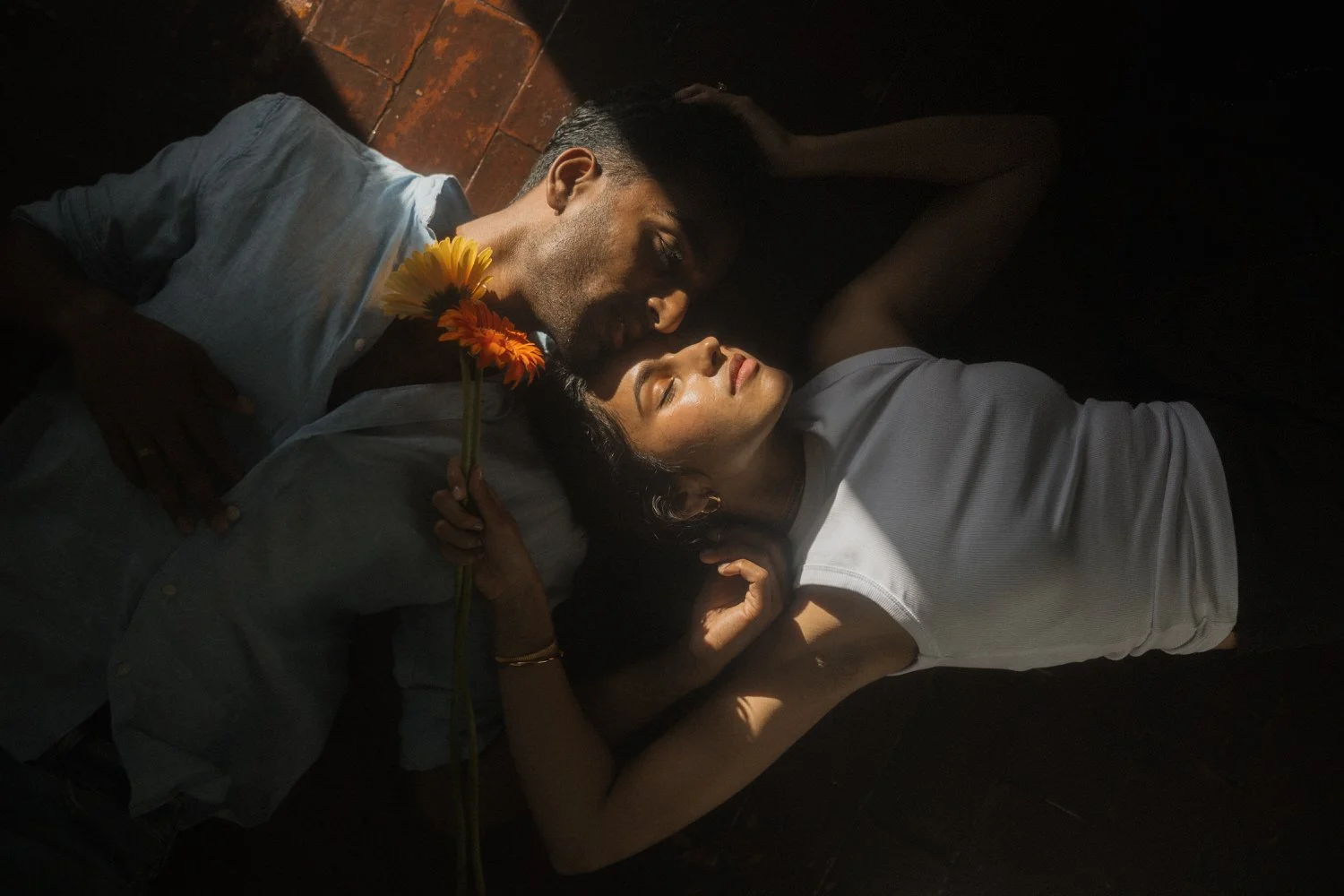 Manoj and Nimisha lying together on the floor holding flowers at their accommodation in São Miguel, Azores