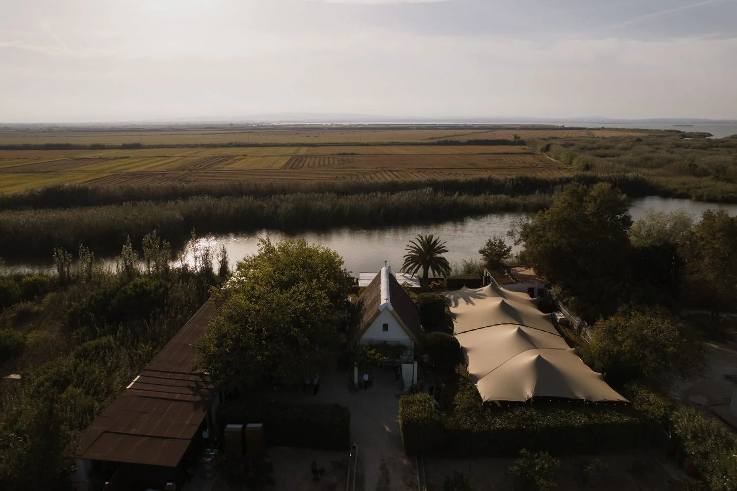 Aerial view of a traditional barraca wedding venue surrounded by rice fields and waterways in Albufera Natural Park, near Valencia.