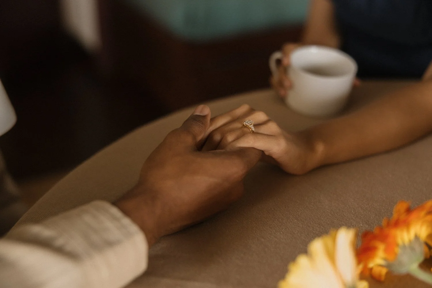 Close-up of Manoj and Nimisha holding hands across the table during a quiet moment in São Miguel, Azores