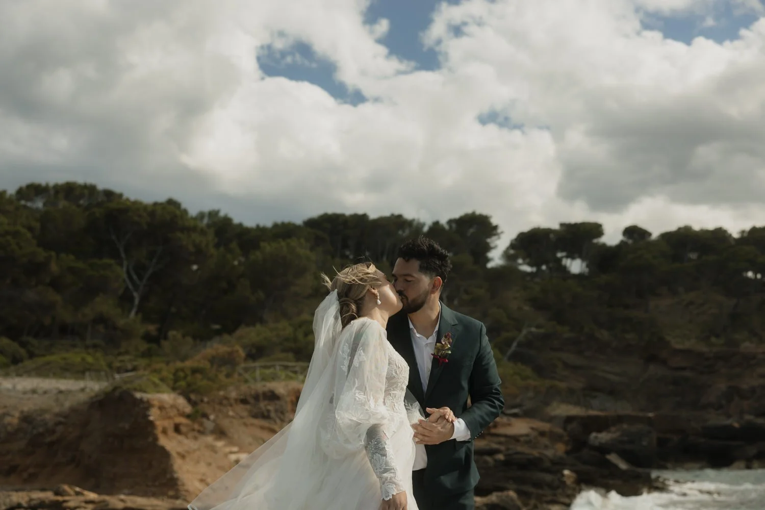 Bride and groom sharing a kiss by the rocky coastline during their intimate Mallorca elopement.