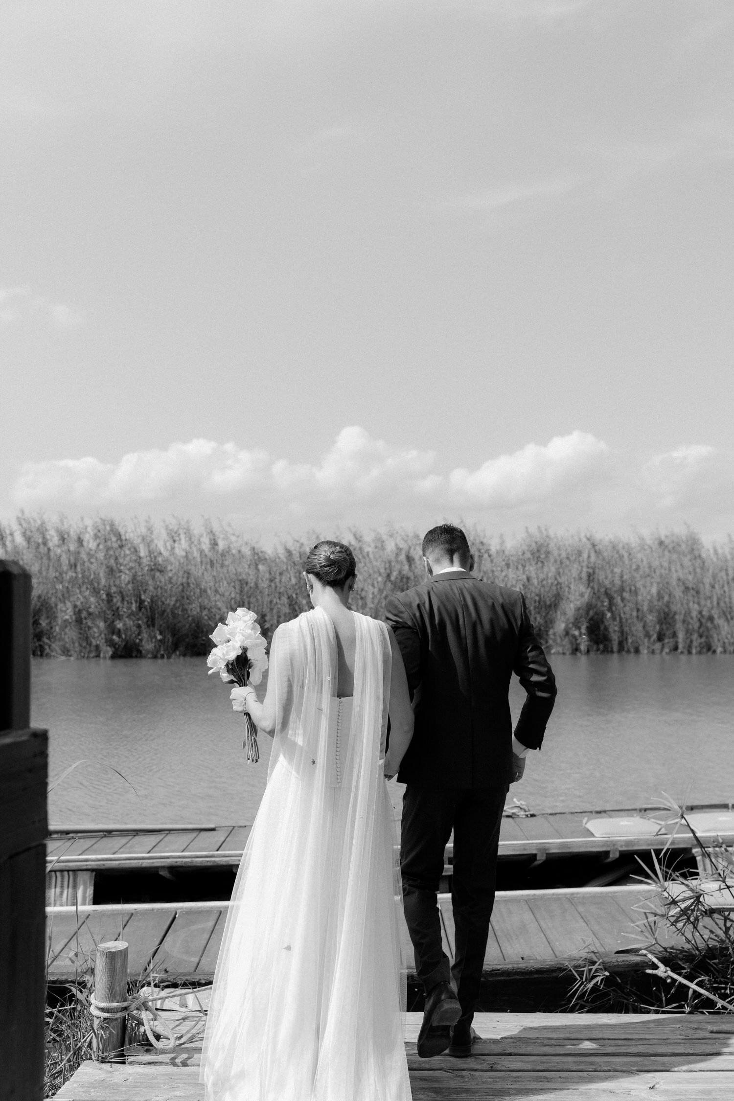 Bride and groom walking together toward the water after the ceremony at La Barraca del Palmar