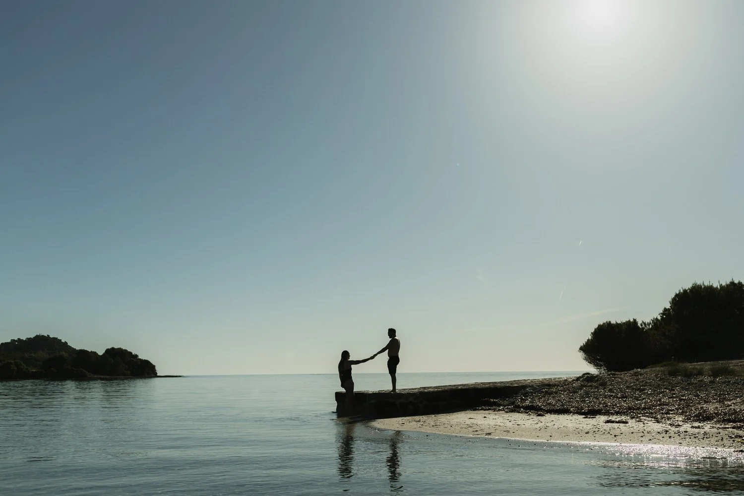 Couple holding hands by the sea during a sunrise experience in Mallorca.