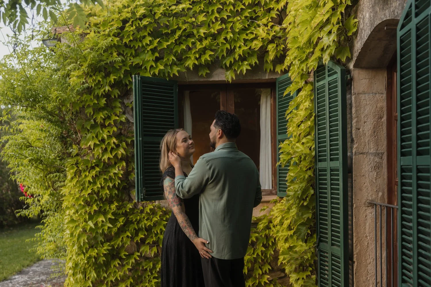 Couple embracing beneath the ivy-covered façade of their countryside finca.