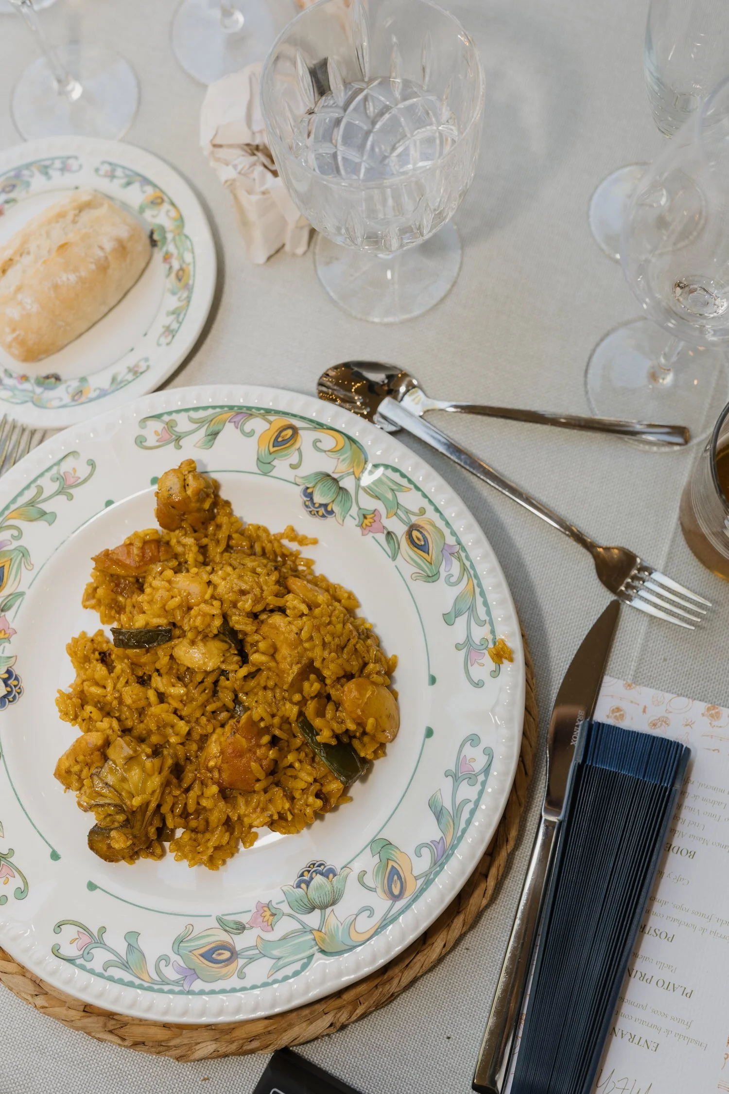 Traditional Valencian paella served on a patterned plate at an elegant wedding table setting.