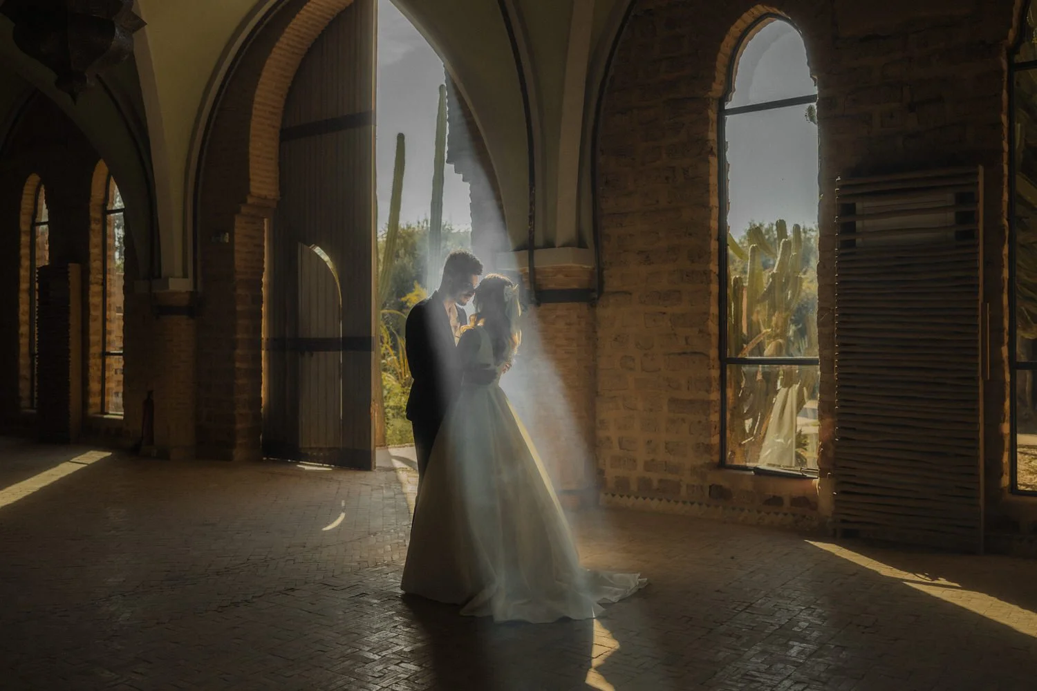 Bride and groom standing in a beam of sunlight inside Beldi Country Club, Marrakech, during their elegant destination wedding.