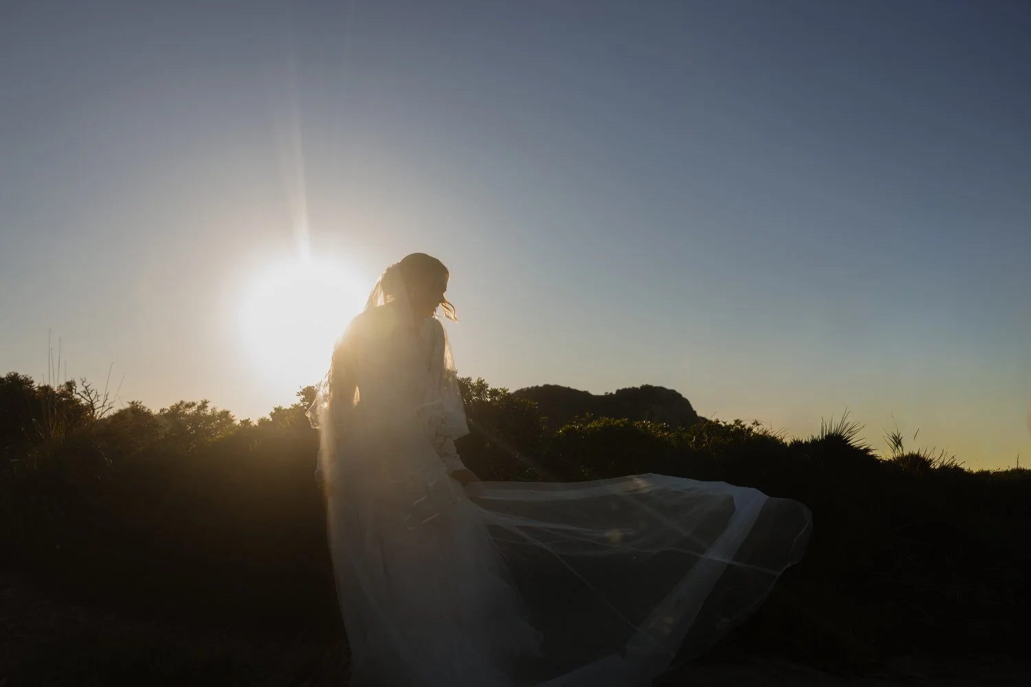 Bride standing at sunset with a flowing veil during an intimate elopement at Cap de Formentor, Mallorca.