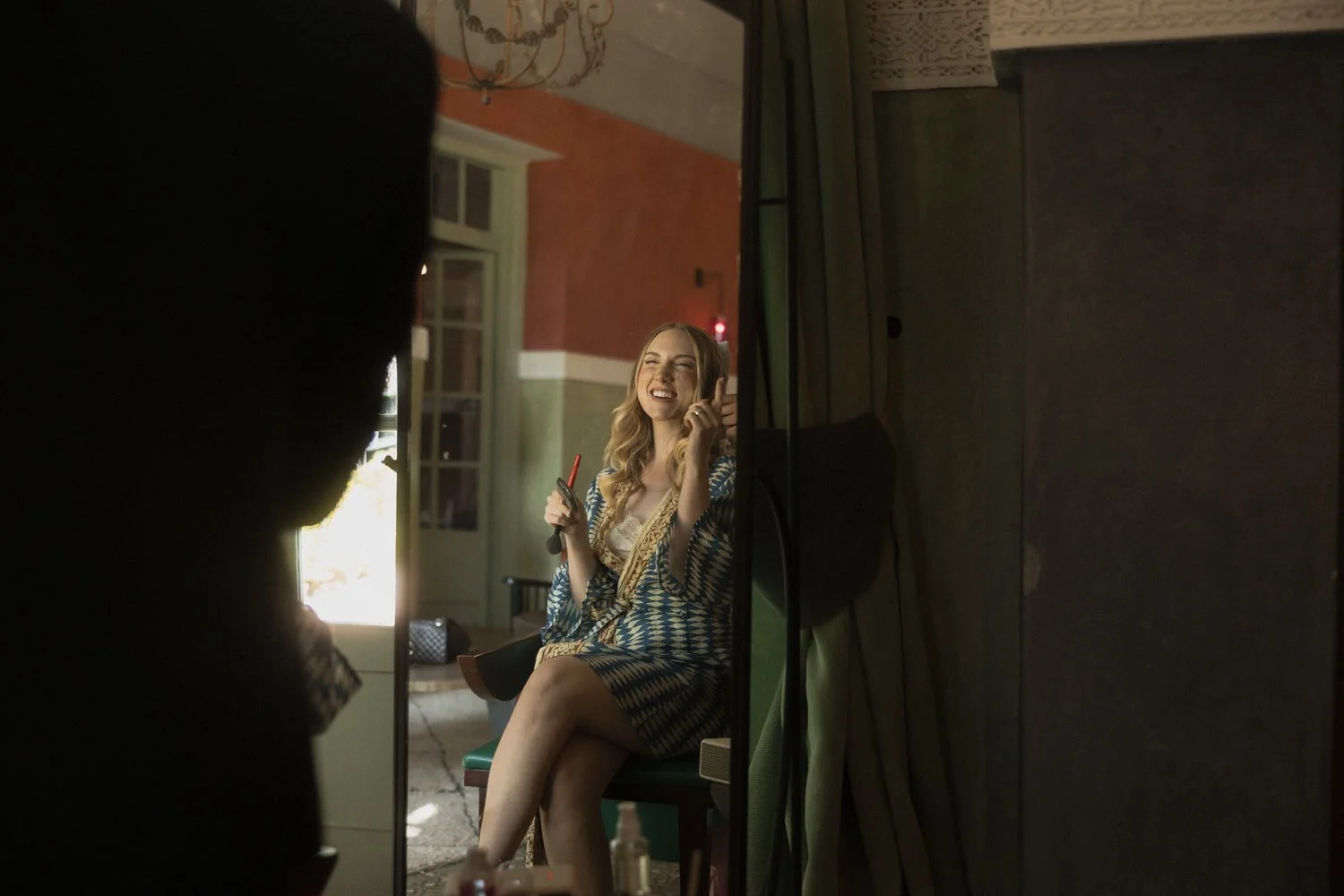 Bride getting ready at Beldi Country Club, smiling while doing her makeup before the wedding in Marrakech