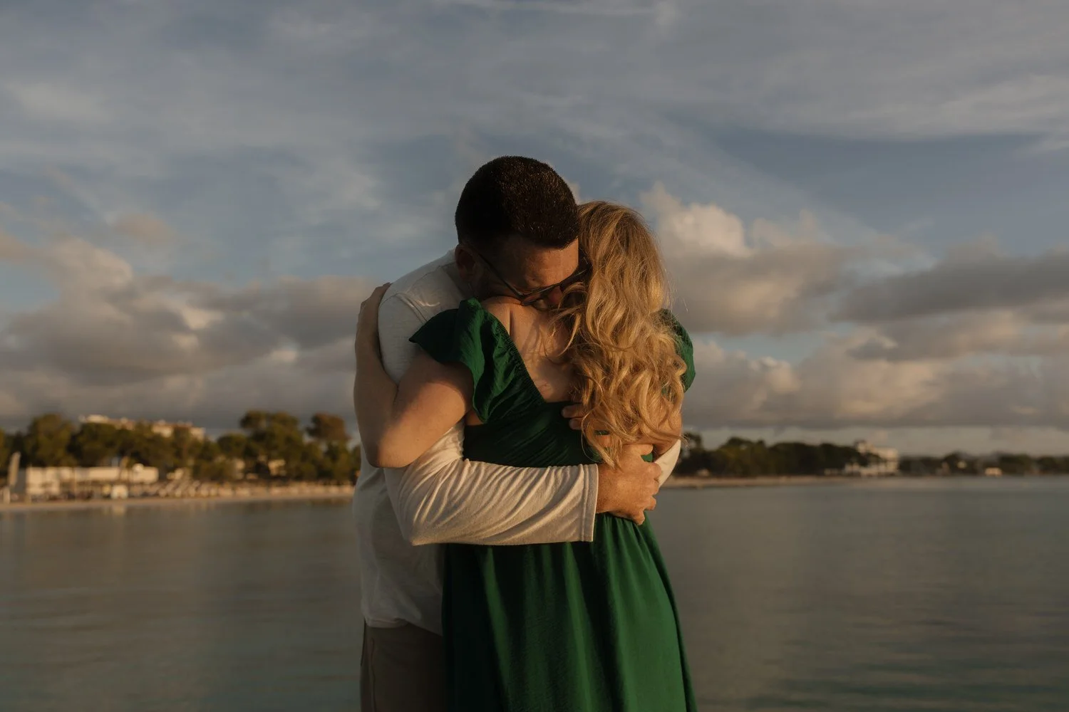 Couple embracing during sunrise on the coast of Mallorca, emotional moment captured during their intimate elopement session.