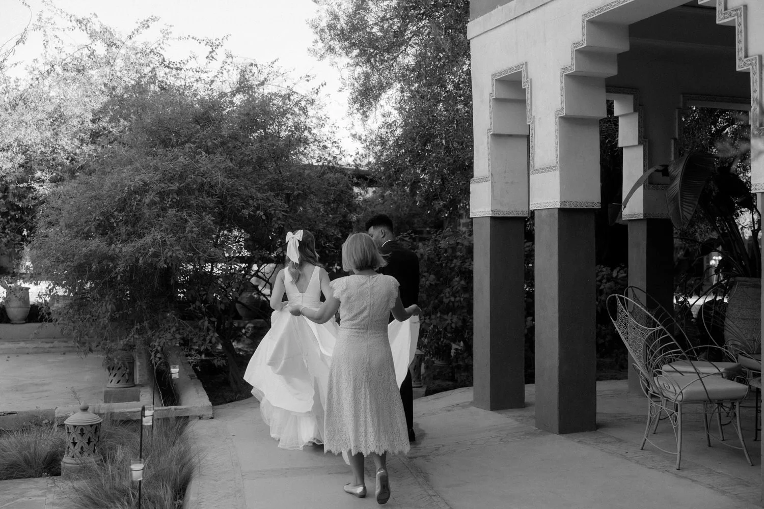Bride walking with her mother and groom through the gardens of Beldi Country Club before the ceremony during a Marrakech destination wedding.