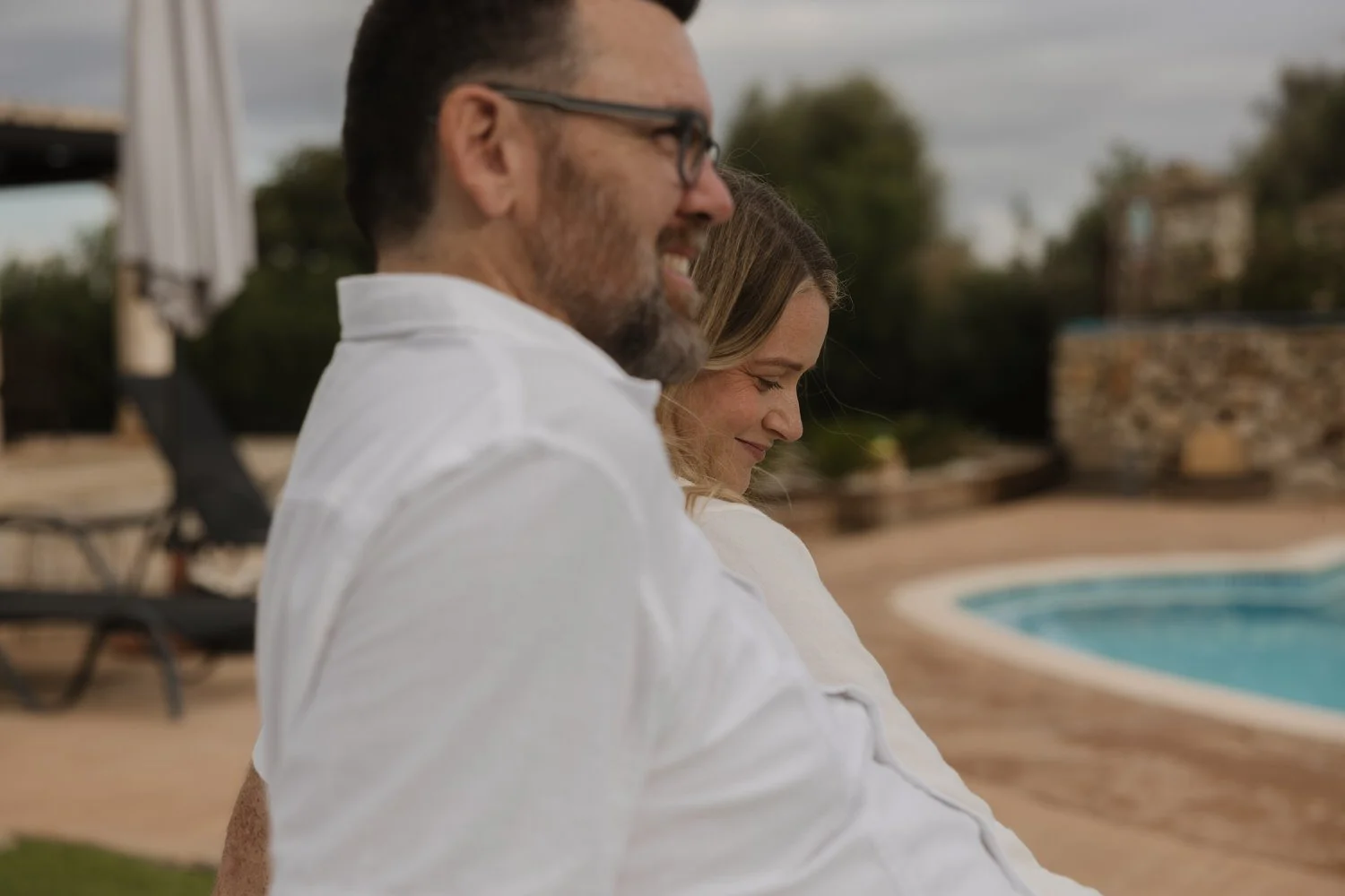 Intimate moment of an elopement couple smiling together by the poolside of their private villa in Mallorca