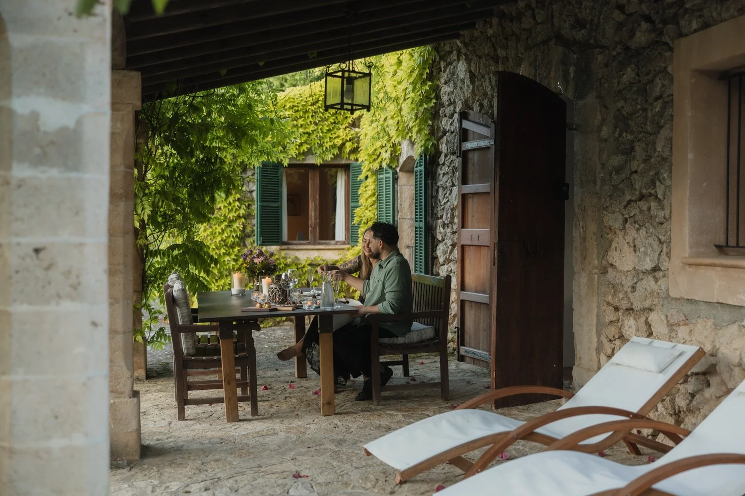 Private candlelit dinner beneath the covered terrace at sunset.