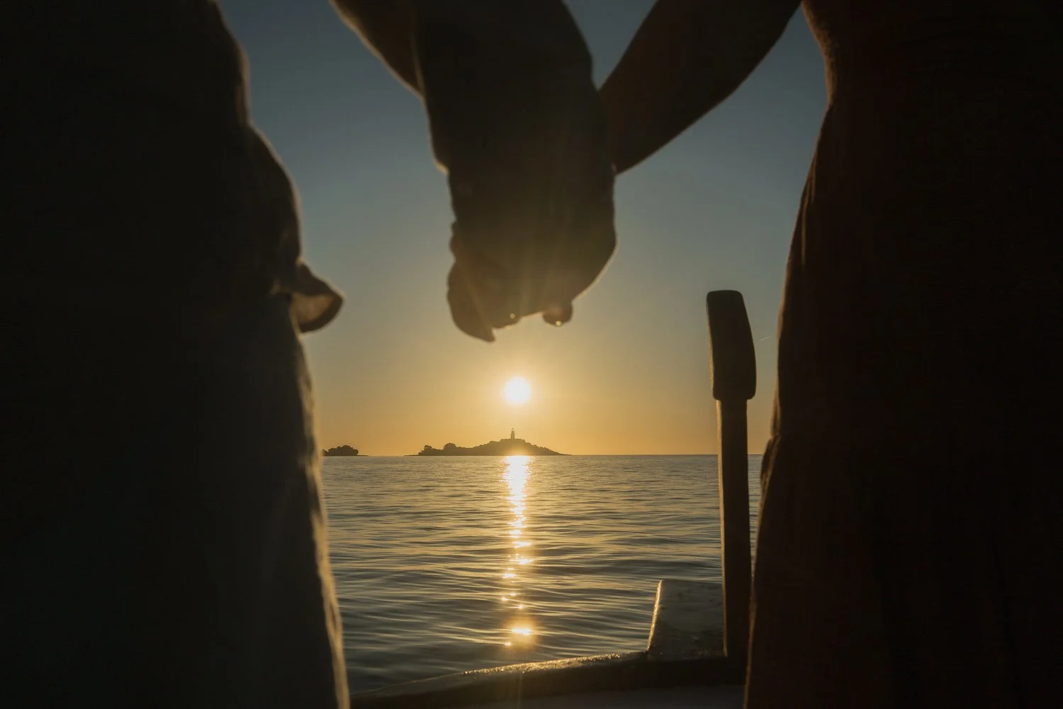 Holding hands at sunrise near a lighthouse on the coast of Mallorca.