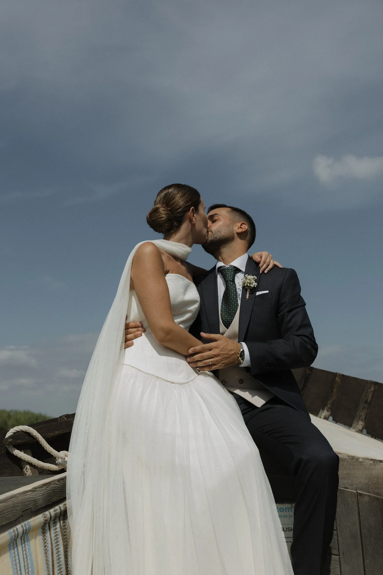 Bride and groom kissing on a traditional boat in the Albufera after their wedding ceremony