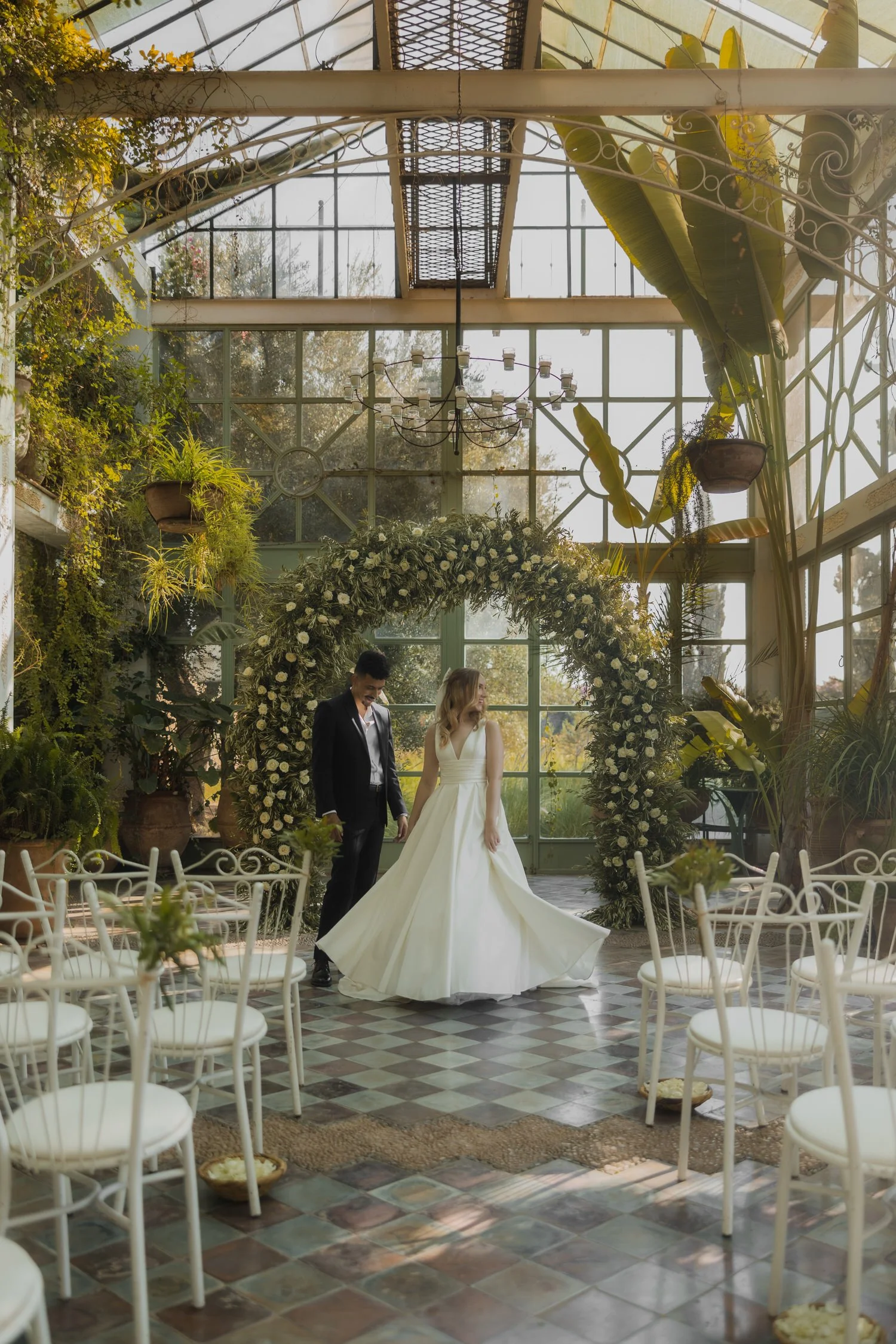Bride and groom standing inside the greenhouse ceremony space at Beldi Country Club during their Marrakech wedding, surrounded by lush greenery and floral arch.