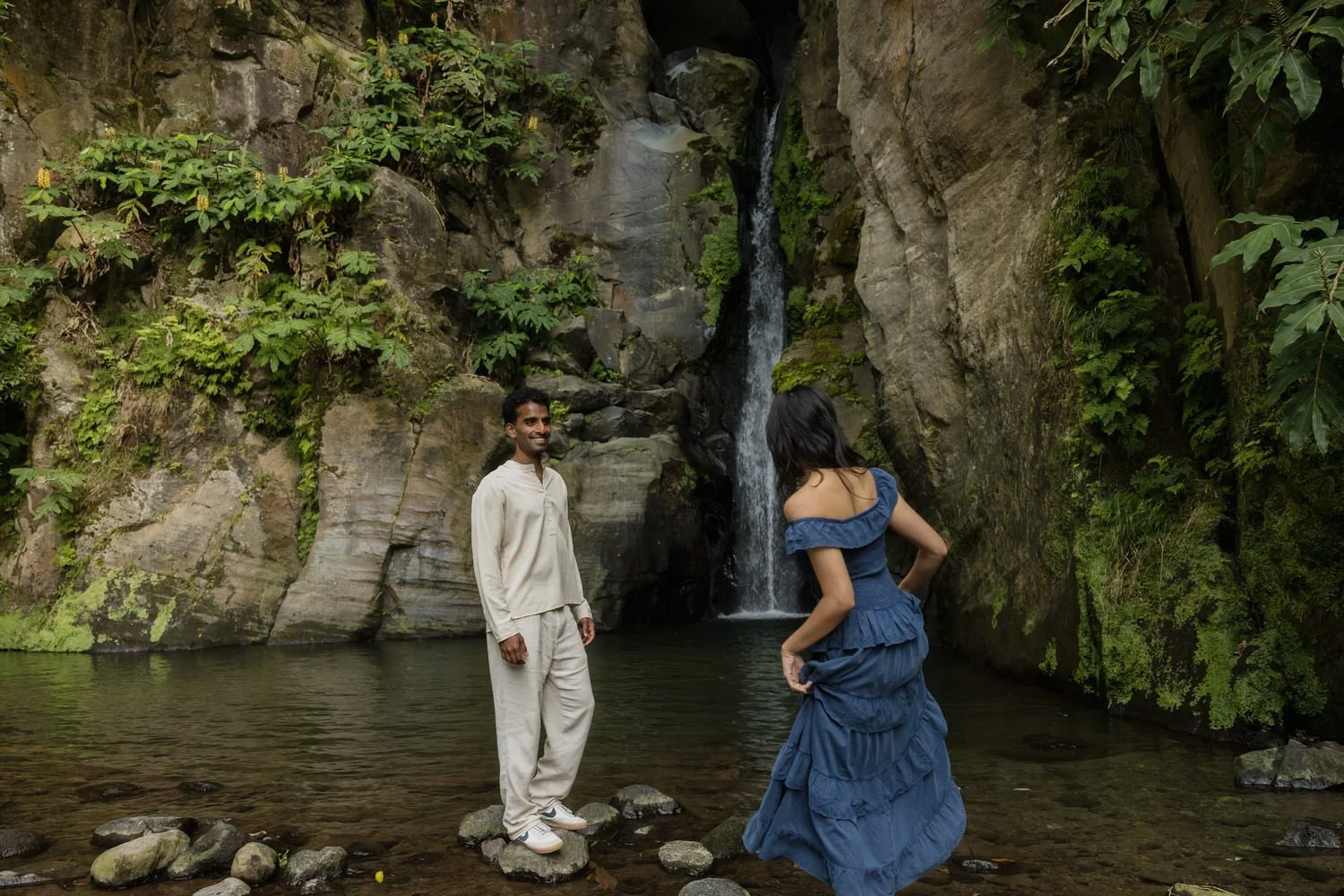 Couple standing by hidden waterfall in lush forest of São Miguel Azores