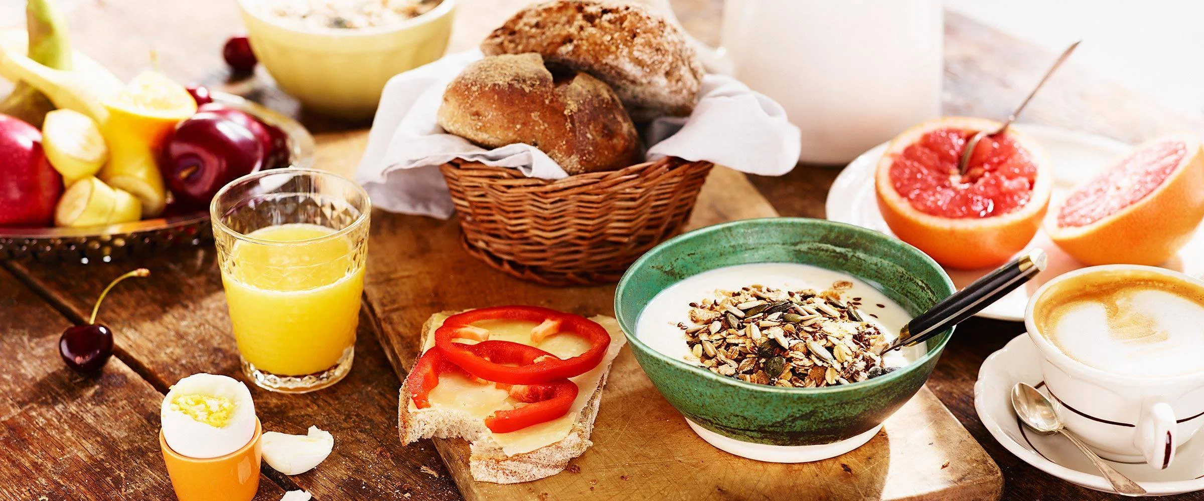 Uppdukad frukost med apelsinjuice, fil, frukt och smörgås.