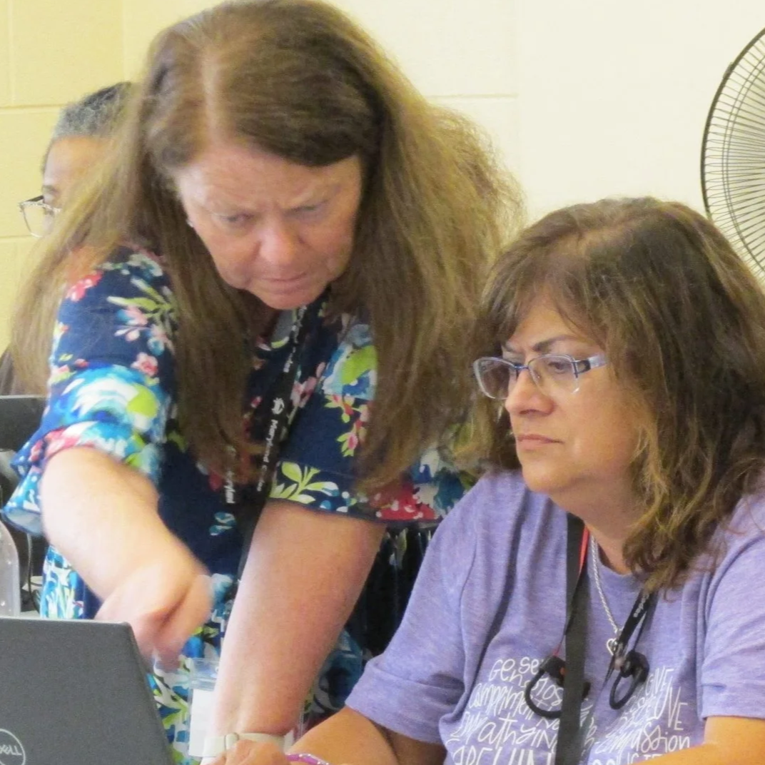two women looking at a laptop, one pointing