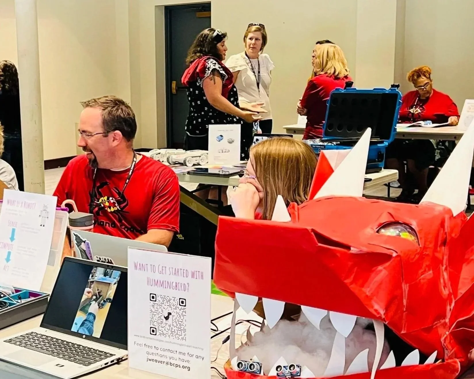 people at tables with a lot materials on them including a large dragon.