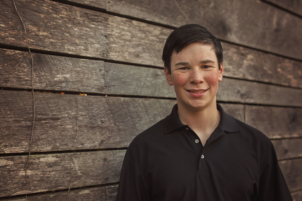  Pinehurst NC son stands near barn for family photos with Candace Wolfenbarger. 