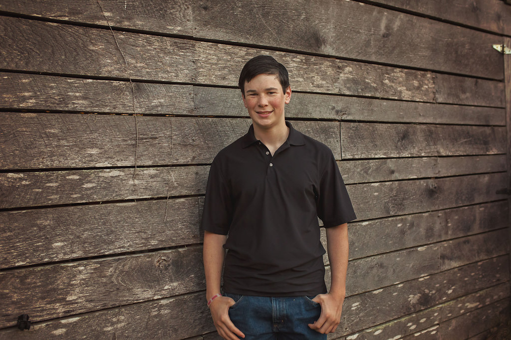  Pinehurst NC son stands near barn for family photos with Candace Wolfenbarger. 