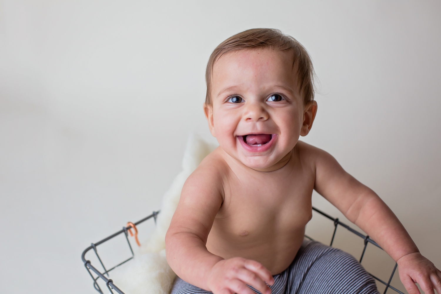 Photo of happy 9 month old baby in basket. Milestone session.