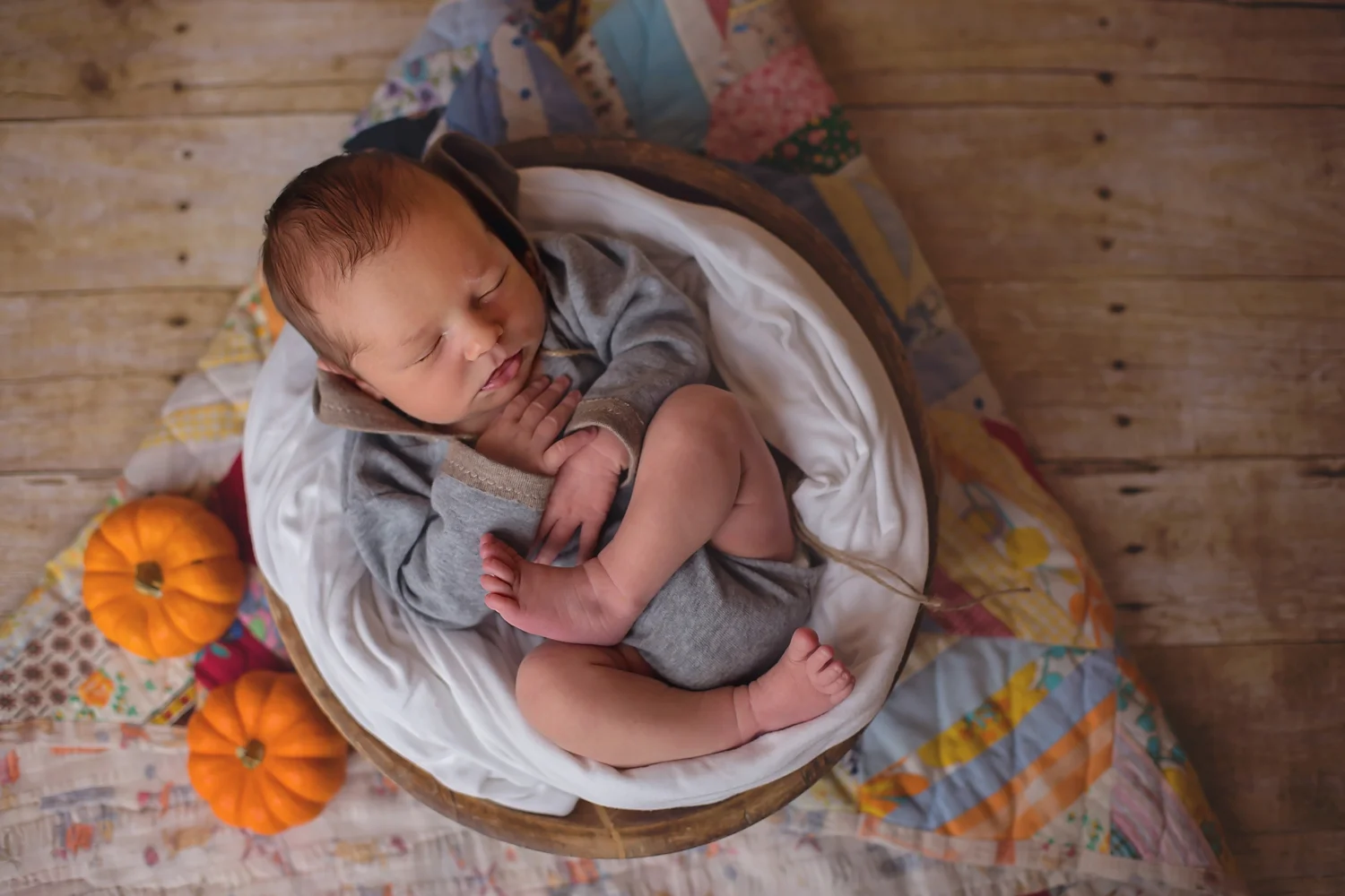 October baby posed in bowl with pumpkins.