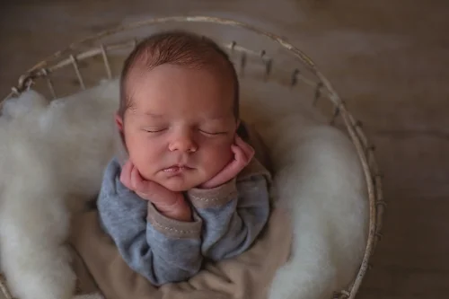 Newborn baby boy rests in basket during studio session in Durham NC. 