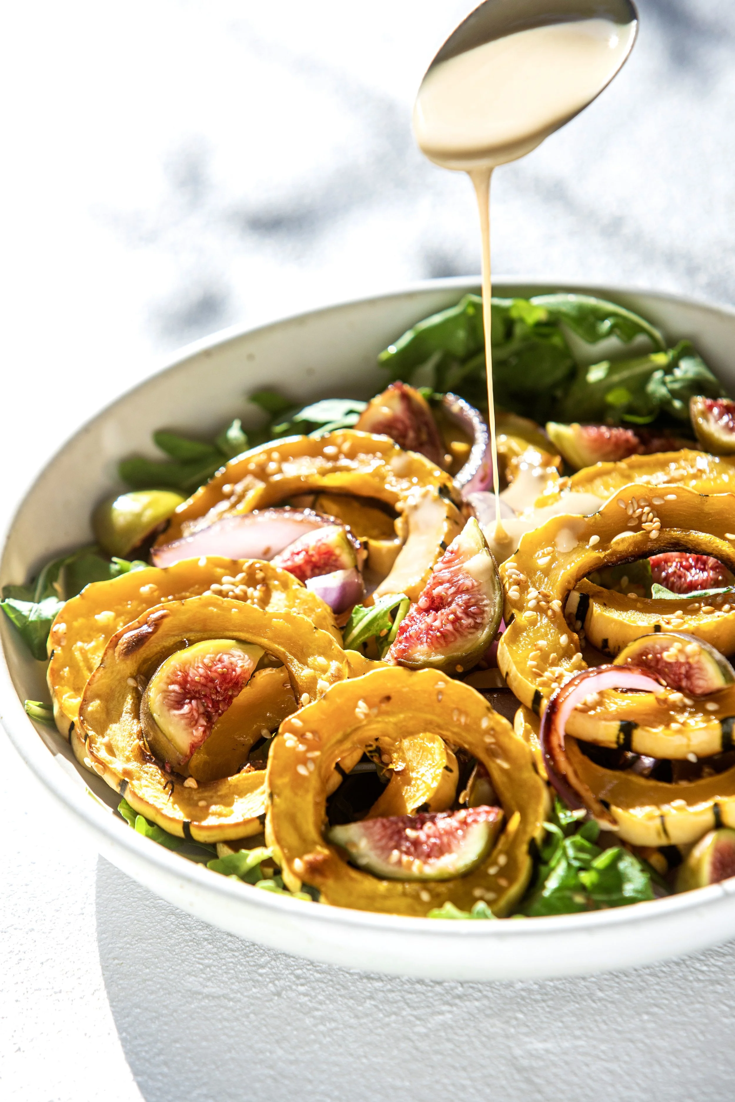 ROASTED DELICATA SQUASH WITH FIGS, ARUGULA, AND TAHINI DRIZZLE