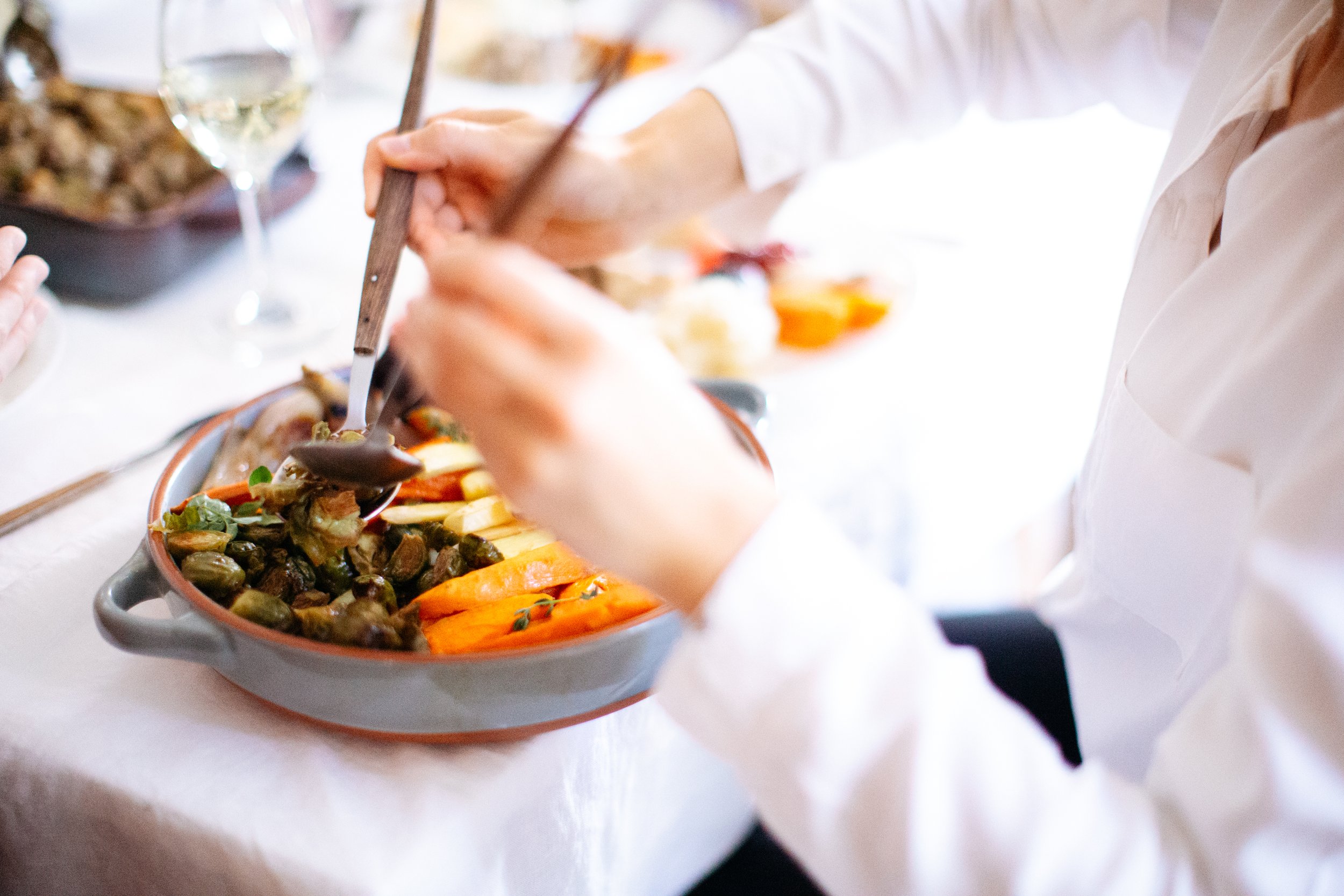 Candid shot of a woman serving food at a dinner party - Photos by Kateland