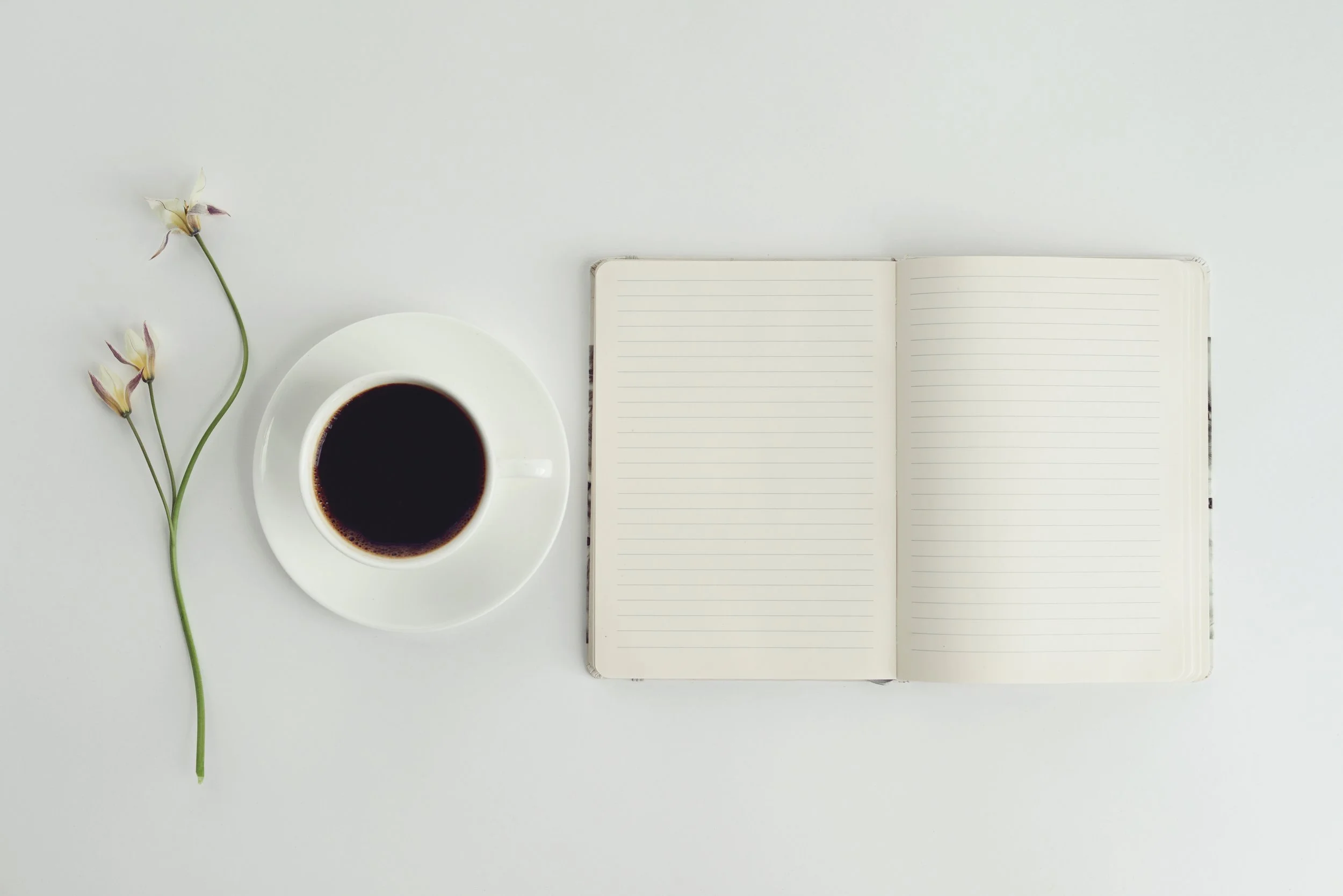 A coffee and an open notebook on a table