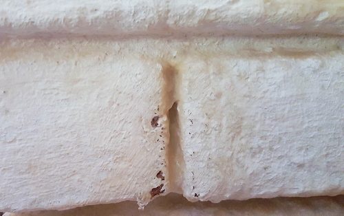 A close-up of the multi-strip remover melting paint off the brick.