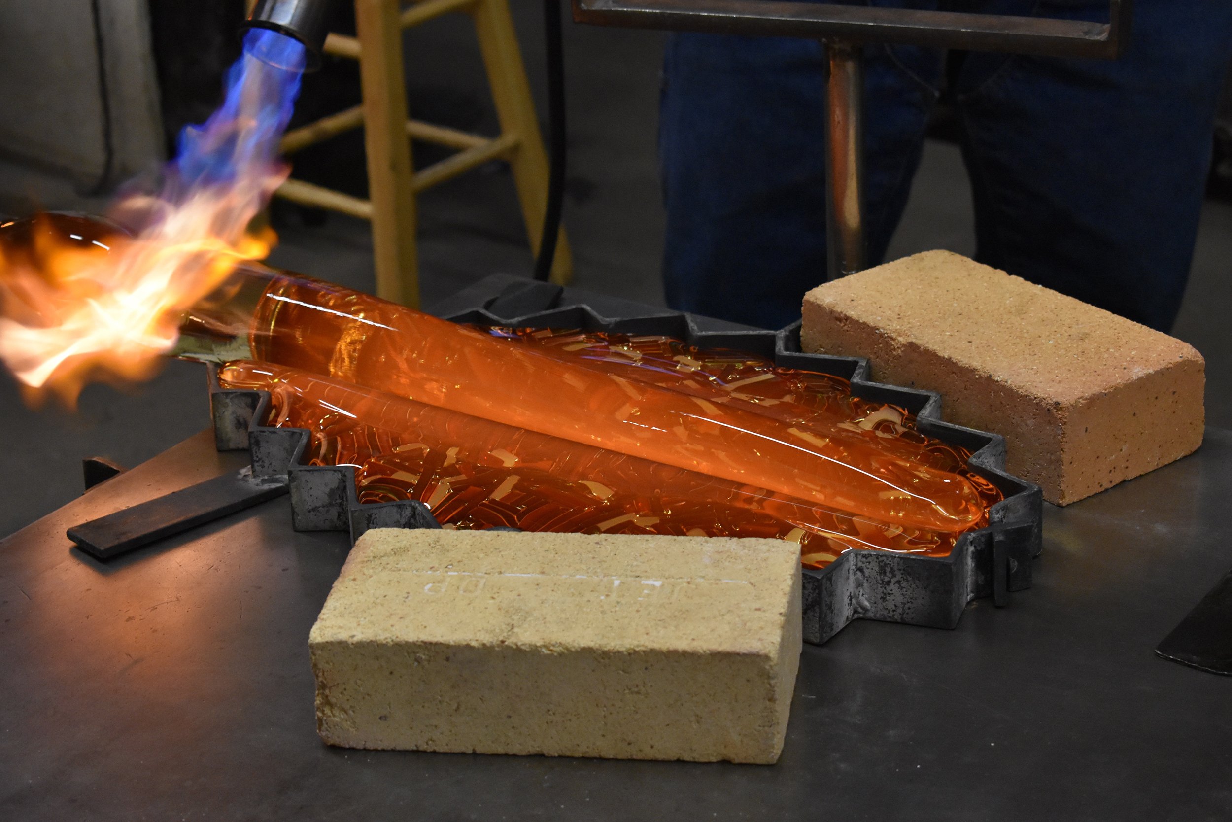 Shaping a glass piece during a demonstration for students.