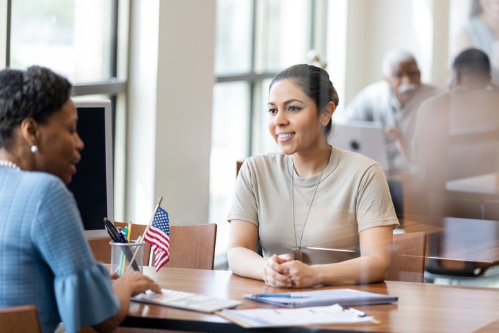 Person speaking with an immigration official across a desk in San Francisco, CA