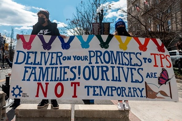 People holding a banner supporting Temporary Protected Status for families in CA