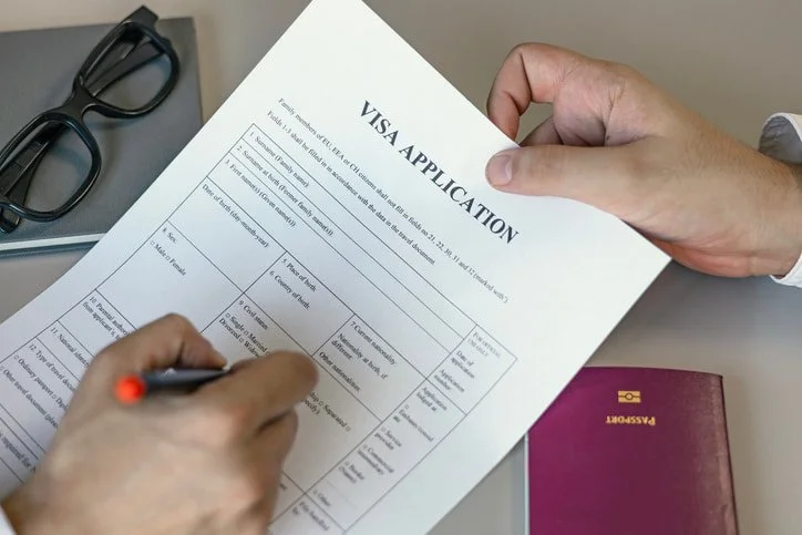 A man filling out a form for a visa application in San Jose, CA
