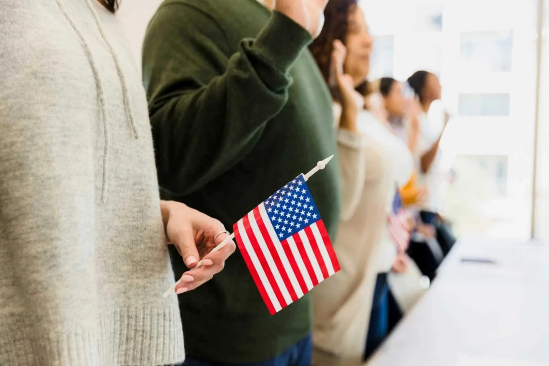 People taking oath holding American flag during US naturalization ceremony and citizen San Jose, CA