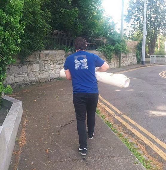 Irish artist Pigsy walks through Ranelagh with a rolled up canvas under his arm