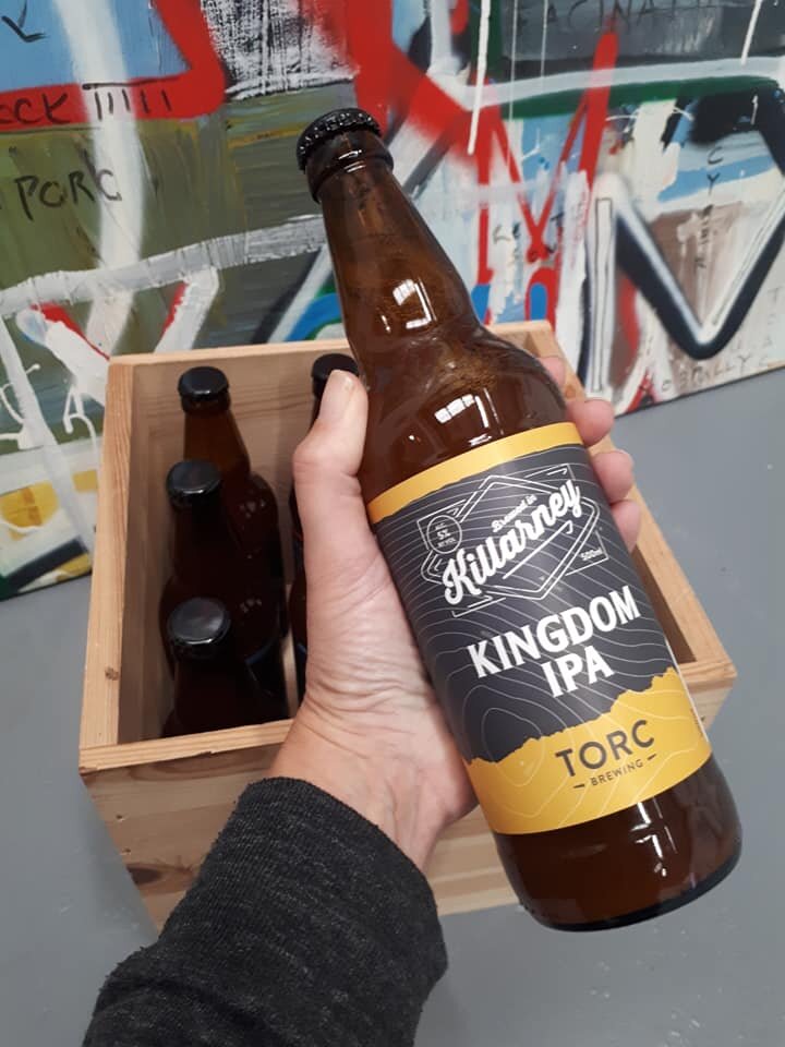 Crate of Torc Beer with a bottle of Kingdom IPA held in front the Killarney beer has a yellow label