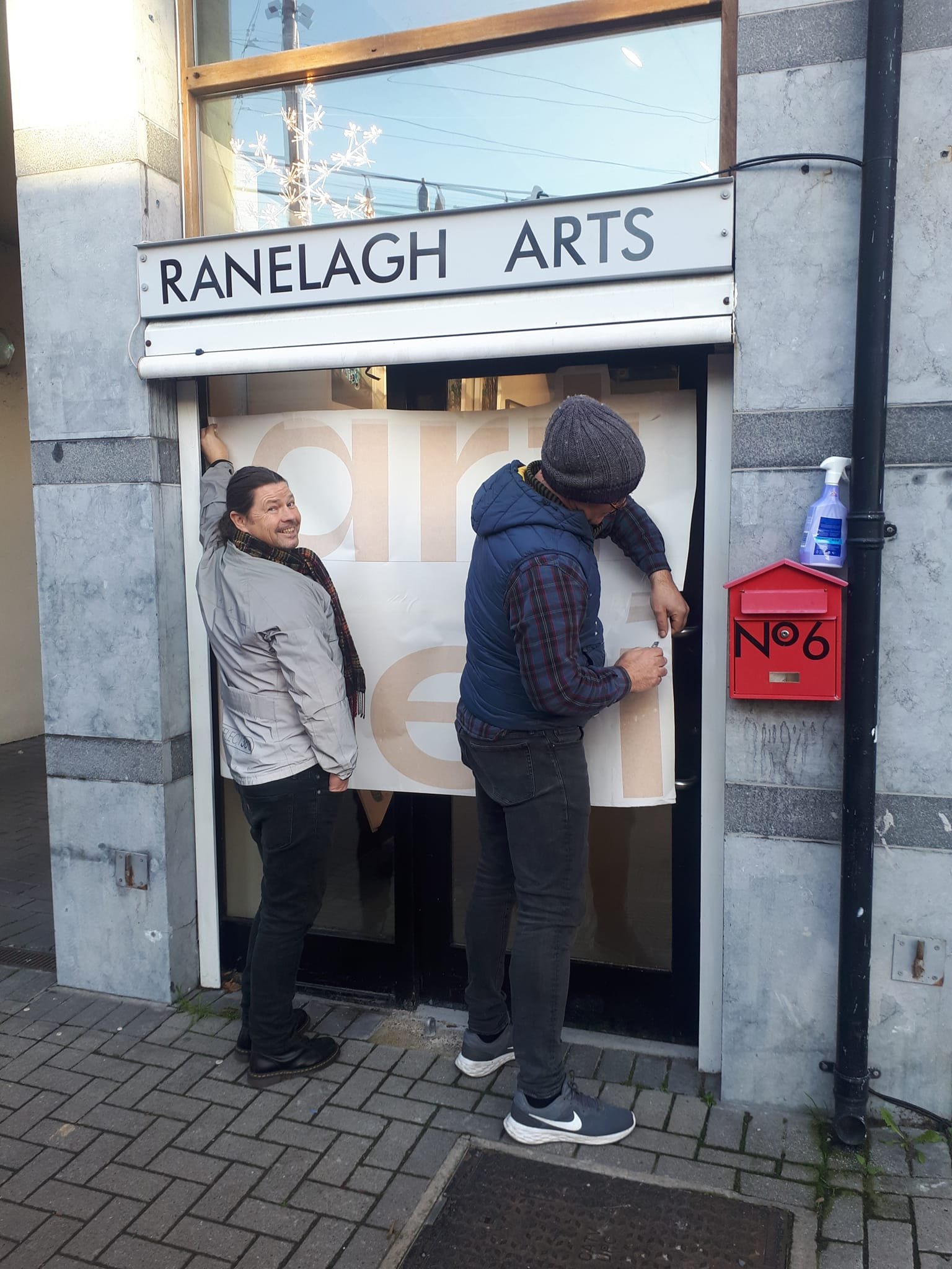 Artists PIGSY and Dan Henson applying decal signage to Ranelagh Arts for Art Deli